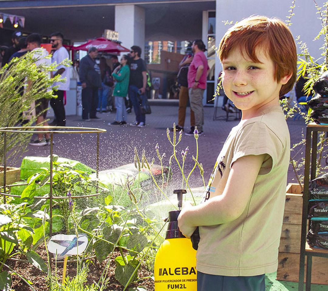 Niños y niñas explorando una huerta interactiva en Expo Cannabis con frutas, verduras y aromáticas
